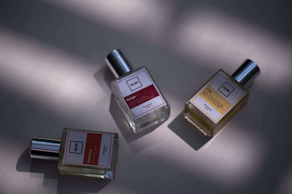 A still life shot of three elegant perfume bottles on a flat surface under soft lighting.
